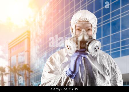 Chinesin Trägt Hazmat-Anzug, Gasschutzmaske und Schutzbrille Vor dem Stadtgebäude. Stockfoto