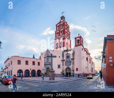 Santiago de Queretaro, Queretaro, Mexiko - 24. November 2019: Sonnenuntergang am Tempel von St. Dominic, mit Menschen zu Fuß Stockfoto