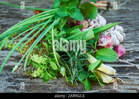 Natürliche frische Kräuter und Gewürze auf rustikalem Holzhintergrund in der Küche für Zutatennahrung / Küche Kräutergartenkonzept Stockfoto