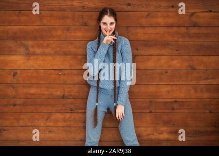 Nahaufnahme des Porträts eines jungen, schönen Teenager-Mädchens, das auf einem Holzwandhintergrund posiert Stockfoto