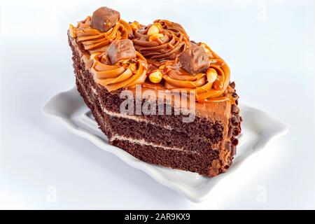 In Scheiben geschnittener Schokoladenkuchen auf weißem Hintergrund. Schokoladenkuchen ist ein Kuchen, der mit geschmolzener Schokolade, Kakaopulver, Karamell und Cremefüllung gewürzt ist Stockfoto