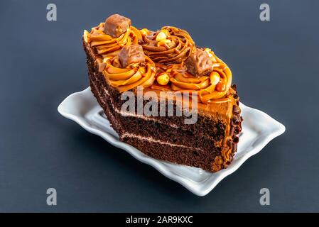 Schokoladenkuchen. Ein Stück Schokoladenkuchen auf grauem Hintergrund. Schokoladenkuchen ist ein mit geschmolzener Schokolade, Kakaopulver und Karamell aromatisierter Kuchen Stockfoto