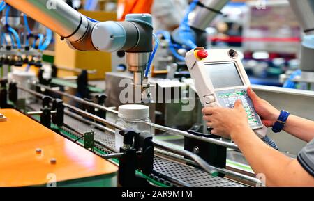 Techniker überprüfen und Steuerung Automatisierung Roboter Arme arrangiert Glas Flasche Wasser auf der automatischen Maschinen und Anlagen in der Produktion im Werk Stockfoto