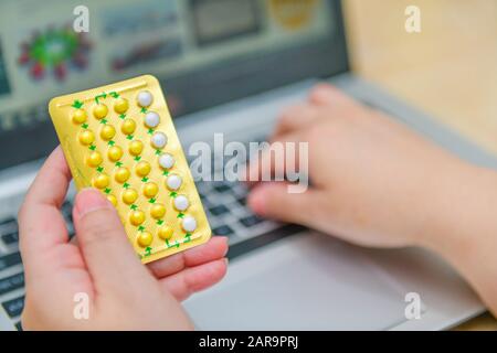 Apotheker, der den Computerlaptop im Apotheke- oder Apothekengeschäft verwendet. Hand, die die Geburtskontrolle hält Pillen packen und die Verordnung angeben. Stockfoto