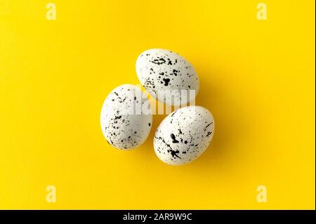 Flache Lay Draufsicht Zusammensetzung aus Eiern mit minimalem Splatterdesign auf gelbem Hintergrund. Grußkarte mit Vorlage für die Osterzeit Stockfoto
