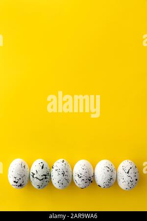 Flache Lay Draufsicht Zusammensetzung aus Eiern mit minimalem Splatterdesign auf gelbem Hintergrund. Grußkarte mit Vorlage für die Osterzeit Stockfoto