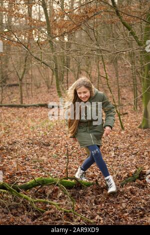 Der junge, glückliche, langhaarige Teenager zieht sich durch den Herbstwald Stockfoto