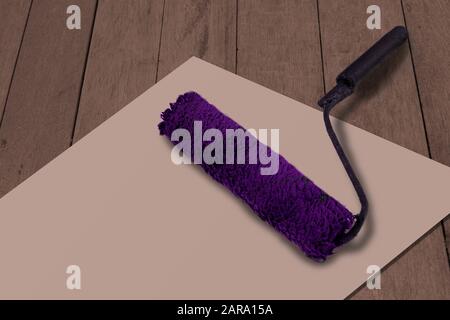 Bürstenrolle auf weißem Papier und Holzhintergrund lackieren. Purple verwendete Farbwerkzeuge als Konzept für die Renovierung, Neugestaltung des Brandings und Änderungen. Verspottete Farbe o Stockfoto