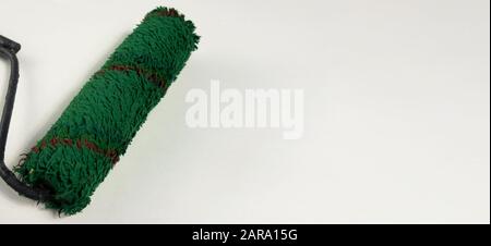 Bürstenrolle auf weißem Hintergrund mit Kopierbereich lackieren. Grün gebrauchtes Farbwerkzeug als Konzept für die Sanierung, Markenumbildung und Änderungen. Kopfzeilenwebsite templ Stockfoto