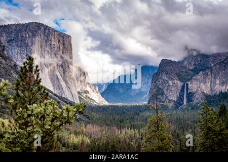 Klassischer Blick auf das Yosemite Valley mit berühmten El Capitan, Cathedral Rocks, Bridalveil Fall und Half Dome und Cloud Rest versteckt hinter den Wolken. Stockfoto