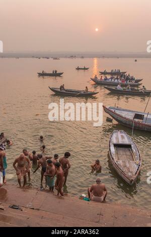 Männer, die bei Sonnenaufgang, bei den Ghats des heiligen Ganges, auch Ganga-Fluss, Varanasi auch Benares, Banaras, Uttar Pradesh, Indien, Südasien, Asien beten Stockfoto