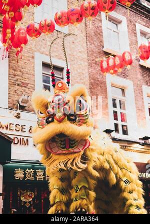 Ein gelber kostümierter tanzender Löwe für chinesische Neujahrsfeiern zum Jahr der Ratte in Chinatown, London. Stockfoto