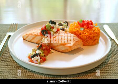 Gegrilltes Lachssteak mit mediterranen Salsa und Safranreis auf weißem Teller Stockfoto