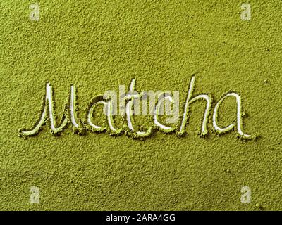 Matcha-Wort über grünem Matcha-Teepulver-Hintergrund. Draufsicht oder flache Lage Stockfoto
