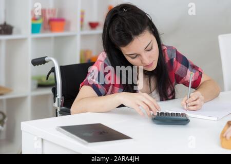 Mädchen im Rollstuhl, die Hausaufgaben machen Stockfoto