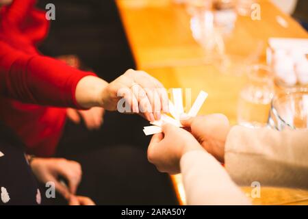 Weibliche Hand, die Papierstreifen zur Vorhersage auswählt. Spiel spielen Stockfoto