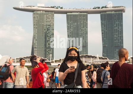 26.01.2020, Singapur, Republik Singapur, Asien - EINE junge Frau bedeckt ihr Gesicht mit einer chirurgischen Maske im Merlion Park in der Marina Bay. Stockfoto