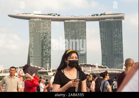 26.01.2020, Singapur, Republik Singapur, Asien - EINE junge Frau bedeckt ihr Gesicht mit einer chirurgischen Maske im Merlion Park in der Marina Bay. Stockfoto