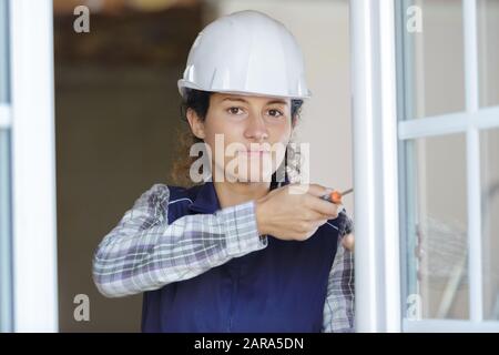 Frau Erbauer verschraubt Fensterrahmen Stockfoto