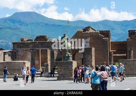 Foro di Pompeji mit der Statue des Centaur & Touristen. Forum der antiken römischen Stadt mit Besuchern unter Ruinen und moderner Bronzestatue. Stockfoto