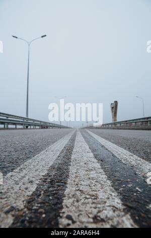 Die Trennlinie auf der Straße ist weiß, die Ansicht von unten auf der Straße, die asphaltiert ist. Straßenmarkierungen auf Asphalt auf der Straße. Stockfoto