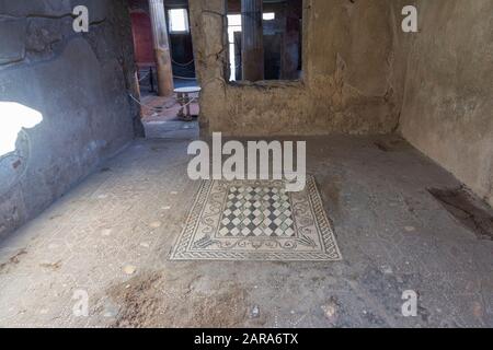 Inneneinrichtung eines antiken Hauses in der römischen Stadt Pompeji mit einem erhaltenen Mosaik auf dem Boden. Stockfoto