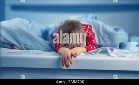 Schlafender Junge im Bett mit blauen Bettungen. Müde Kinder im Schlafzimmer Stockfoto