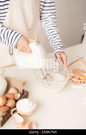 Männliche Hände schlagen Eiweiß Creme mit Mixer in der Schüssel Stockfoto