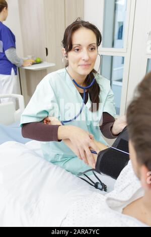 Krankenschwester, die Druck eines Patienten im Krankenhausbett übt Stockfoto