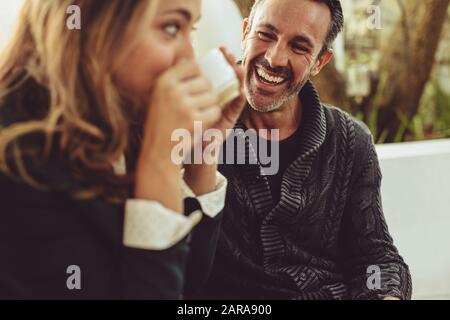 Lächelnder Mann, der seine Freundin beim Kaffeetrinken betrachtet. Ein Paar sitzt im Coffeeshop. Stockfoto