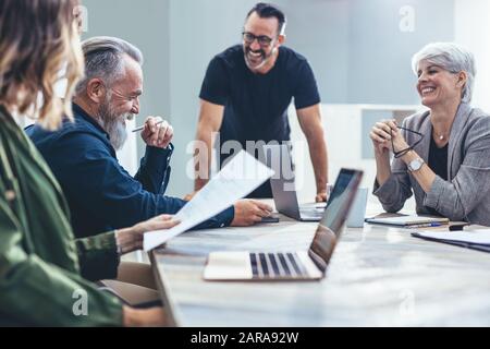 Team von Unternehmensexperten, die sich zu einem neuen Projekt treffen. Geschäftsleute lächeln während eines Meetings im Konferenzraum. Stockfoto