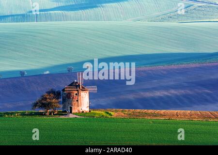 Wunderschöne ländliche Landschaft mit alter Windmühle und grünen sonnigen Quellhügeln. Region Südmähren, Tschechien Stockfoto