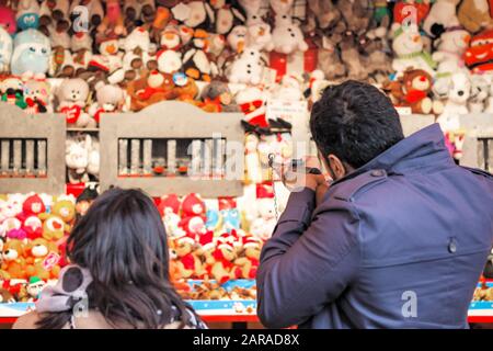 London, Großbritannien - 27. November 2019 - Rückblick auf Touristen, die Schießspiele spielen, um Plüschspielzeug an der Wand zu gewinnen, um Weihnachten lustige Winterwunderländer zu besuchen Stockfoto