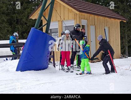 Ein junger Skifahrer erhält Hilfe von einem Begleiter auf dem T-Bar Surface Skilift. Skigebiet Rogla, Slowenien. Stockfoto