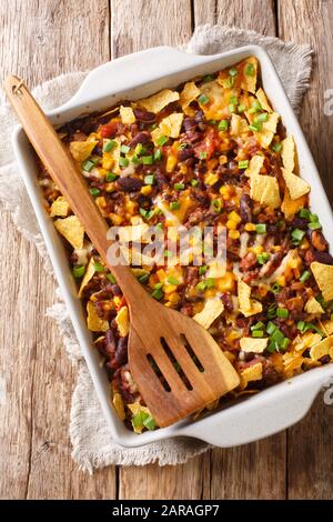 Mexikanische Frito-Pastete mit gemahlenem Rindfleisch, Käse, Gemüse und Pommes in einer Backform auf dem Tisch. Vertikale Draufsicht von oben Stockfoto