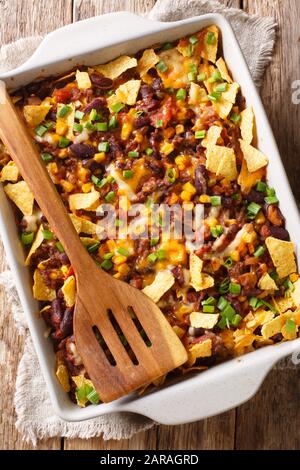 Kitschiges Frito Pie Rezept mit gemahlenem Rindfleisch, Bohnen im Ranch-Stil, Käse und Enchilada-Sauce, die in einer Backform auf dem Tisch gebacken werden. Vertikal Stockfoto