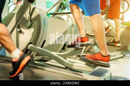 Gruppe von Leuten, die im Fitnessclub auf Tapis roulant trainieren - Fitness-Mann läuft und mit eliptischem Crosstrainer - Wellness- und Körperbaukonzept Stockfoto