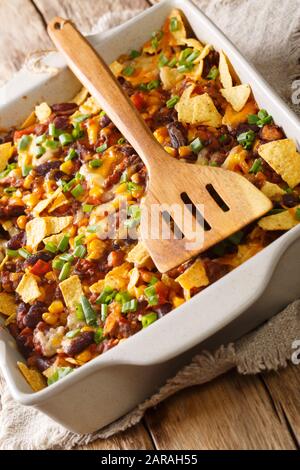 Mexikanische Frito-Pastete mit gemahlenem Rindfleisch, Käse, Gemüse und Pommes in einer Backform auf dem Tisch. Vertikal Stockfoto