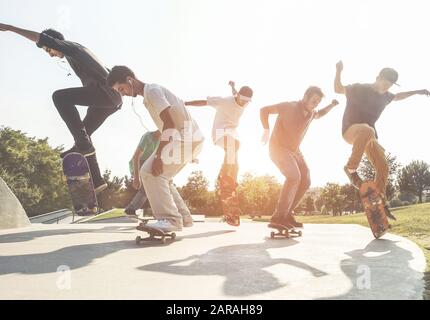 Skater springen mit Skateboard im Stadtvorstadt Park - Sportliche Jungs, die bei Sonnenuntergang im städtischen Wettbewerb Tricks und Fertigkeiten ausführen - Extremsport und Jugend li Stockfoto