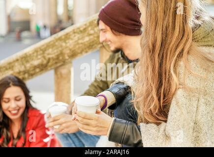 Junge Leute, die Kaffee auf Papier toben, nehmen die Tasse im Treppenhaus im Freien im Stadtzentrum weg - Drei Freunde, die Cappuccino trinken - Winterkonzept Stockfoto