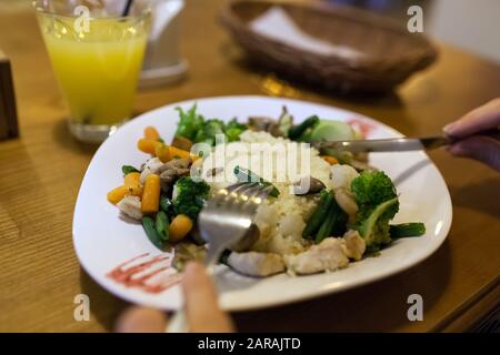 Couscous mit Huhn, frisches Gemüse serviert mit Saft im Restaurant. Gericht mit Karotten, Brokkoli, Pilzen Stockfoto