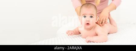 Baby Massage Banner. Junge Therapeuten geben einen Jungen den Rücken massieren. Baby Massage Konzept auf weißem Hintergrund mit kopieren. Stockfoto