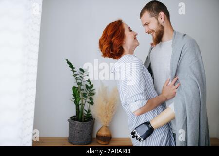 Glückliches Ehepaar verliebt sich zu Hause, steht dicht, schaut einander an Stockfoto