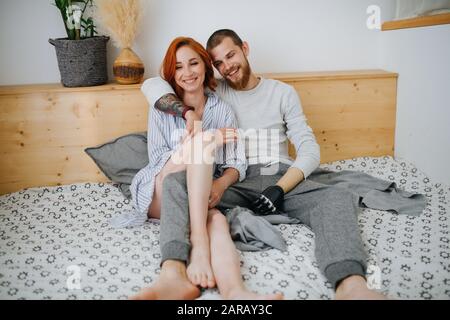 Glückliches Ehepaar, das zu Hause auf ein Doppelbett kühle Stockfoto
