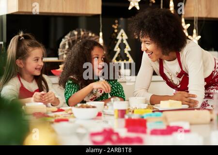 Süße Mädchen, die mit Hilfe ihrer Mutter Plätzchen backen Stockfoto