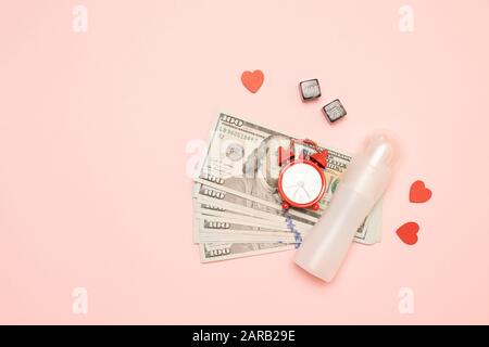Viel Geld, Wecker, würfelförmige Einrichtung und Schmiermittel auf pinkfarbenem Hintergrund. "Love for Money"-Konzept Stockfoto