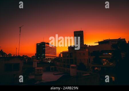 Stadtbild mit rotem Hintergrund bei Sonnenuntergang (Fotografiert in Tel Aviv, Israel. Rathaus im Zentrum) Stockfoto