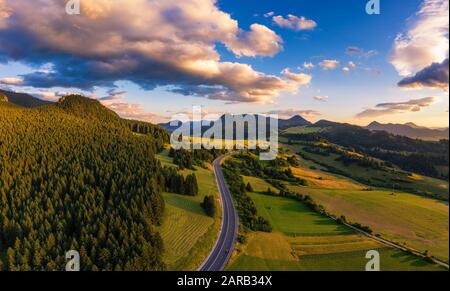 Straße, die bei Sonnenuntergang durch Wälder der Region Liptov in der Slowakei führt Stockfoto