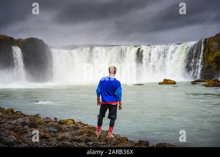 Wanderer, der am Wasserfall Godafoss in Island steht Stockfoto