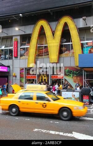 New YORK, USA - 10. JUNI 2013: Gelbe Kabine fährt entlang Des Times Square McDonald's fast Food Restaurants in New York. Stockfoto